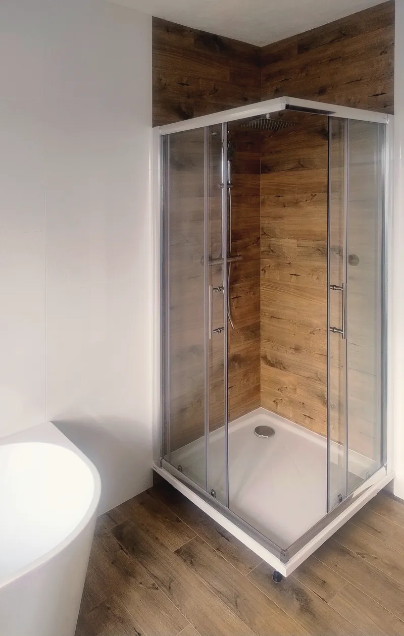 Sprchový kút obložený drevodekorom až nad zástenu, biele steny